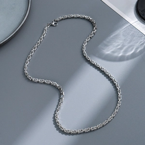 Close-up of a 6mm silver Byzantine Cuban link chain with detailed woven metal texture