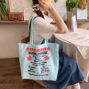 Close-up of light blue canvas tote bag with vintage red and blue printed graphics