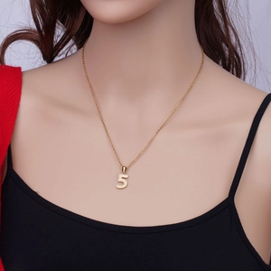Détail d'un collier avec le chiffre angélique 5 doré porté sur un mannequin poli
