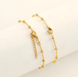 Close-up of gold beaded chain bracelet with cubic zirconia pendant and lobster clasp