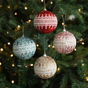 Glitter Christmas foam balls with white lace trim hanging on a festive tree branch