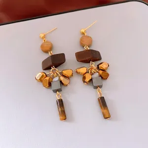 Bohemian silver needle earrings with wood beads and tiger eye stone tassels on grey background