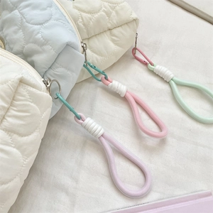 Close-up of heart-shaped quilted makeup bag with colorful braided rope zipper pull