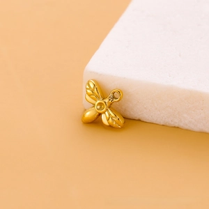 Vue détaillée d'une breloque abeille dorée pour bijoux DIY sur une surface en pierre