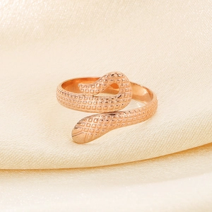 Macro shot of rose gold snake ring with realistic scale texture on champagne silk