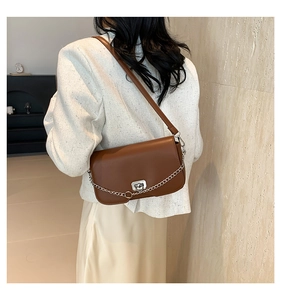 Detailed side view of a brown leather shoulder bag with silver chain and metal clasp