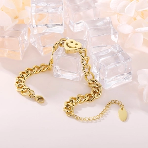 Détail d'un bracelet gourmette doré avec pendentif cœur sourire sur glace et fleurs séchées