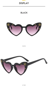 Detail of heart sunglasses with black frame, golden flower accents and gradient lenses