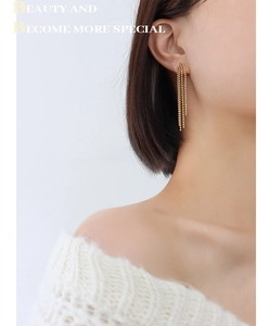 Boucles d'oreilles à pampilles en chaîne dorée plaquée or 18 carats portées par un mannequin
