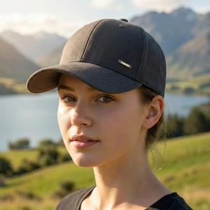 Men's dark grey baseball cap with golden metal fashion badge in scenic outdoor setting