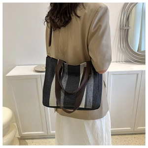 Detail of striped canvas tote bag showing adjustable shoulder strap and woven texture