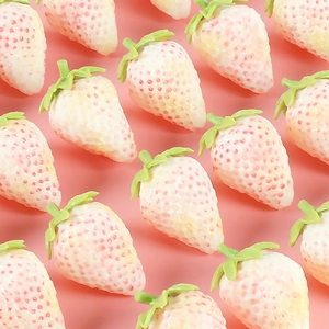 Realistic artificial creamy white strawberries with pink tips on a vibrant pink background