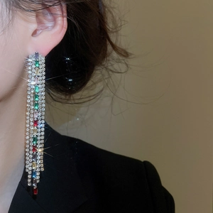 Close-up of elegant long zircon tassel earrings with colorful square gems on model