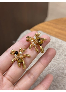 Detailed view of 18K gold plated tiger eye stone earrings with small pearls on hand