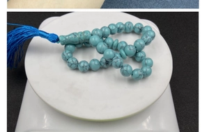 Close-up of blue-green marble beads prayer bracelet with a deep blue tassel on a scale