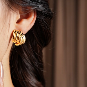 Close-up of gold geometric intertwined hoop earrings with thick layered metal texture