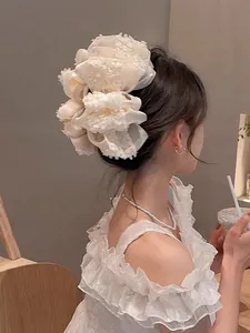 Détail d'une grande pince à cheveux fleurie multicouche crème sur l'arrière de tête