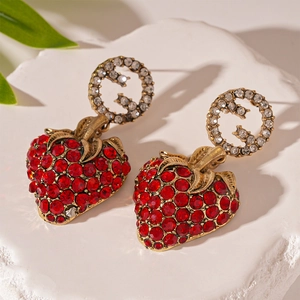 Macro view of vintage gold strawberry earrings with red crystals and G logo detail