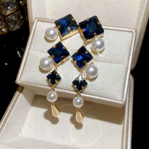 Close-up of diamond-set rhombus pearl water drop earrings in a jewelry storage box