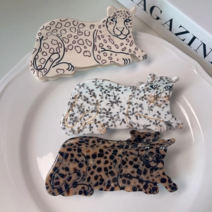 Three leopard-shaped acetate hair claws in beige and tortoiseshell on a white plate