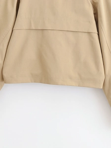Close-up of khaki trench coat showing precision double stitching and premium fabric texture