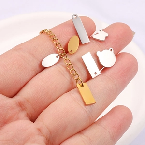 Polished stainless steel pendants and gold chains held in hand for DIY jewelry making