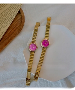 Detail view of gold stretch band watches with pink dials on a vintage tray
