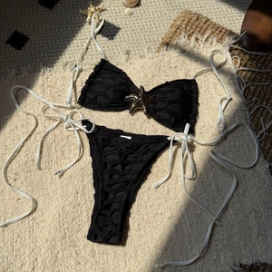 Sexy black and white mesh bikini set with starfish gold hardware on sand-colored texture