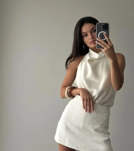 Détail d'un ensemble élégant en satin avec haut licou et mini-jupe blanche brillante
