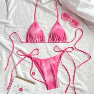 Detailed flat lay of pink tie-dye bikini set with string ties and decorative accessories