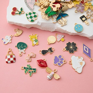 Detail shot of colorful enamel DIY charms with animal and plant designs on a pink display