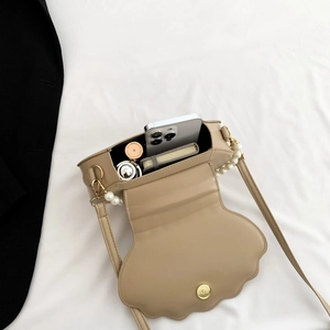 Interior storage view of khaki shell-shaped crossbody bag with pearl chain strap