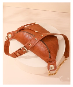 Detailansicht braune PU-Tasche mit Goldkette und Strickzug auf beigem Sockel präsentiert