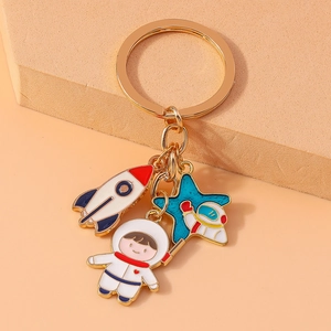 Golden keychain with cute cartoon astronaut, rocket and blue star enamel charms