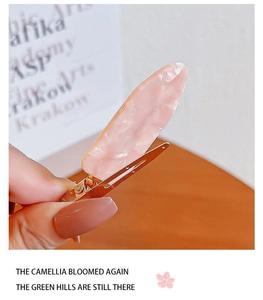 Detailed macro view of pink marble texture acetate hair clip with a gold metal duckbill base