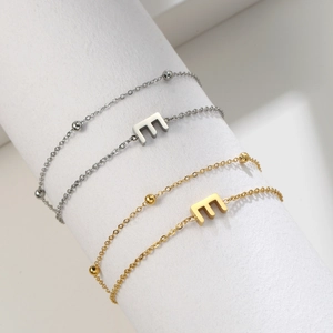 Detail of silver and gold stainless steel bracelets with letter E charms and beads