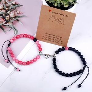 Detail of pink and black matte beaded magnetic heart bracelets for couples on cards