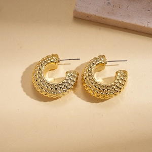 Detail of 18K gold-plated C-shaped earrings with textured bubbly metal design