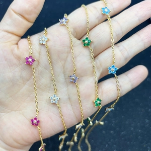 Detail of gold flower necklaces with colorful crystal petals held in a hand