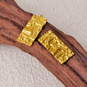 304 stainless steel gold rectangular textured charms on wood with a natural fabric background