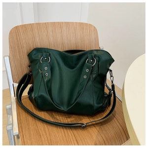 Detail of dark green tote bag with silver hardware and leather texture on a wooden chair