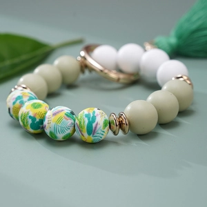 Detail of sage green and ivory silicone beads with cactus patterns and silk tassel