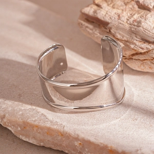 Polished silver wide cuff bracelet with smooth edges on a natural stone base
