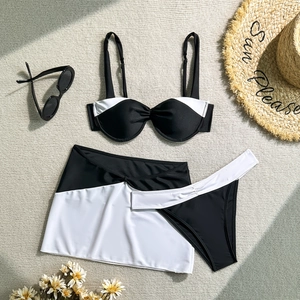 Three-piece black and white contrast bikini set with tie-up sarong on a woven mat