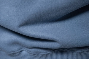 Macro shot of blue knitted fabric texture and ribbed hem detail on the casual sweatshirt