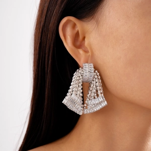 Macro detail of sparkling silver tassel earrings with zircon fringe on a model's ear