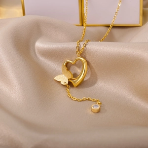 Detail of 18k gold heart and butterfly pendant with zircon on champagne silk background