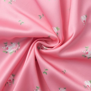 Macro shot of pink floral satin fabric showing silky texture and white red floral pattern