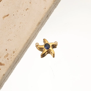 Close-up of golden starfish pendant with a blue gemstone on a neutral stone background