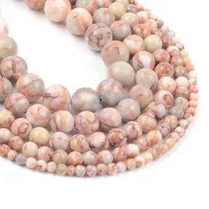 Macro shot of assorted natural stone beads in white and orange with marbled texture
